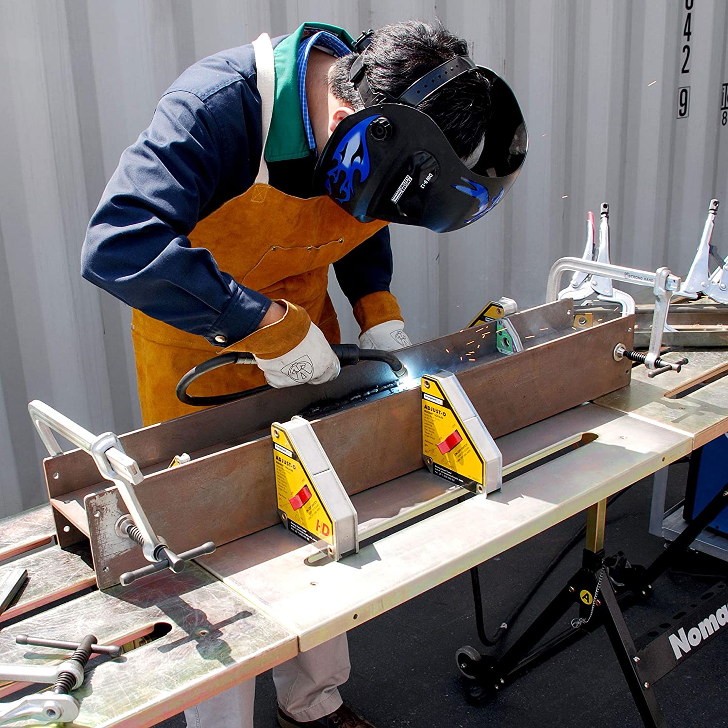 Soudeur assemblant une pièce bridée sur une table de soudage avec équerres et serre-joints